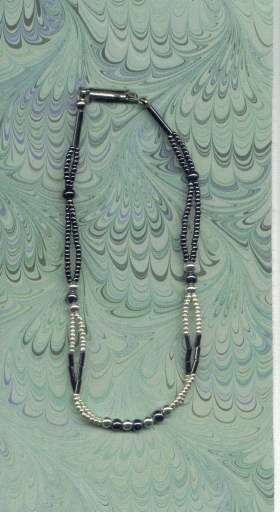 Double strand silver and glass gunmetal  round and bugle beads. Lobster-claw clasp.